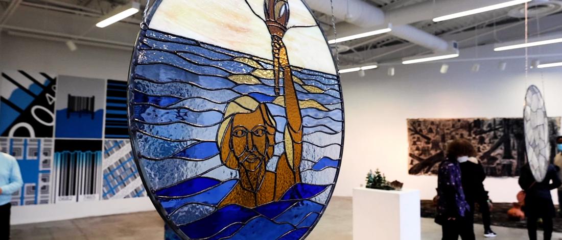 Stained glass artwork featuring a person emerging from the water holding a torch.