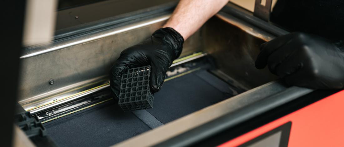 Technician pulls 3D print out of 3D printer bed