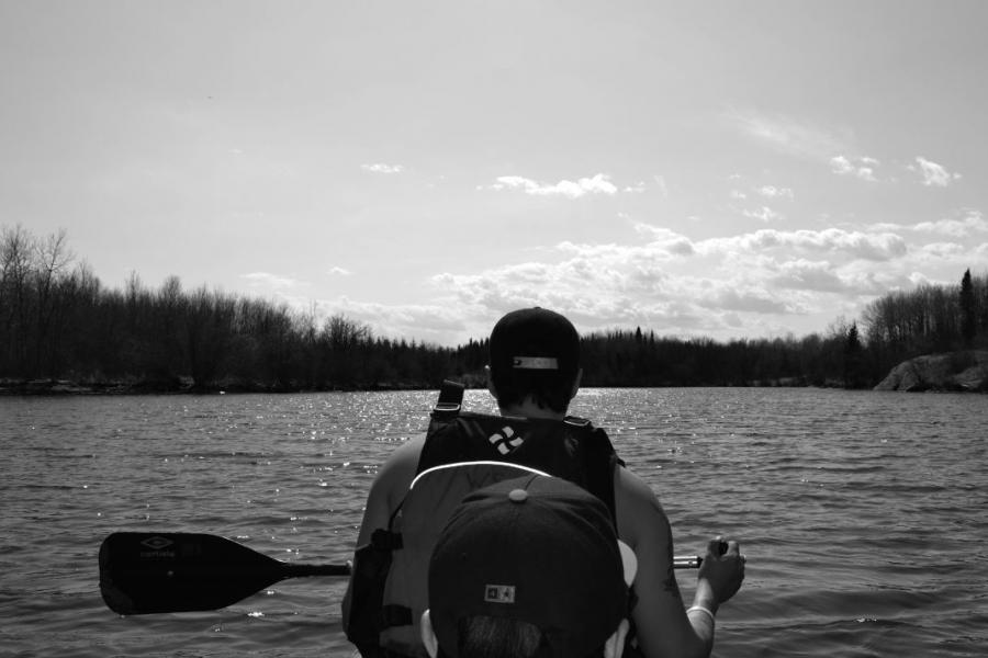 guy from behind paddling on a canoe in black and white