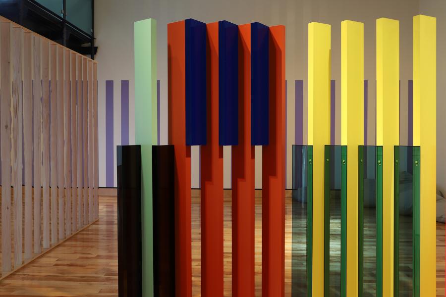 Image of red and yellow fence-like art installation in a gallery space.