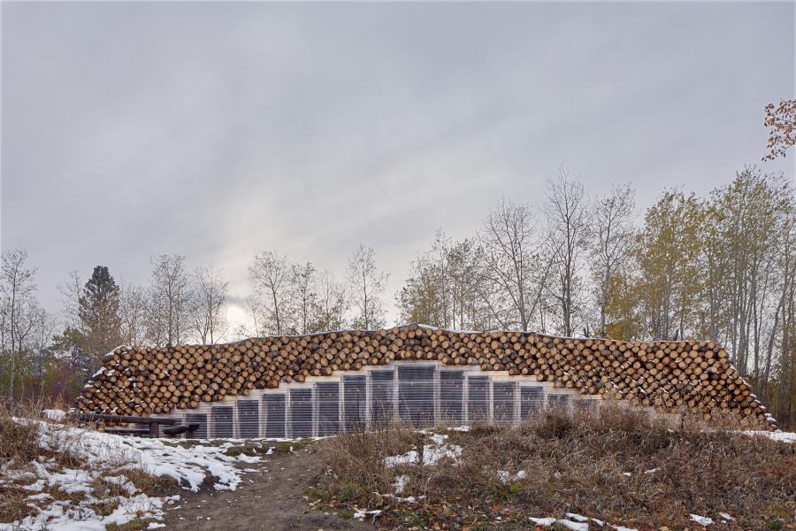 Image of structure with log roof in an autumn landscape.
