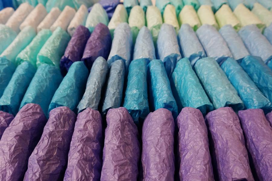 Folded tissue paper, display in a rows from blue to purple in colour.