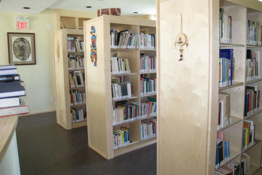 An interior view of the Manitoba Indigenous Cultural Education Centre's Library with rows of bookshelves filled with books.