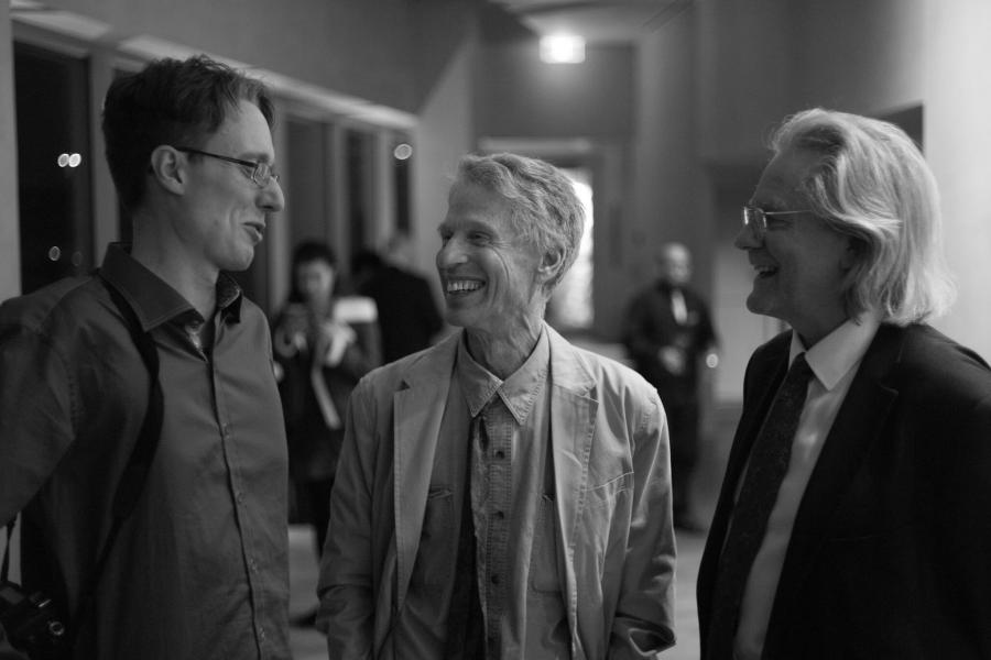 Photo of 3 men in close conversation.