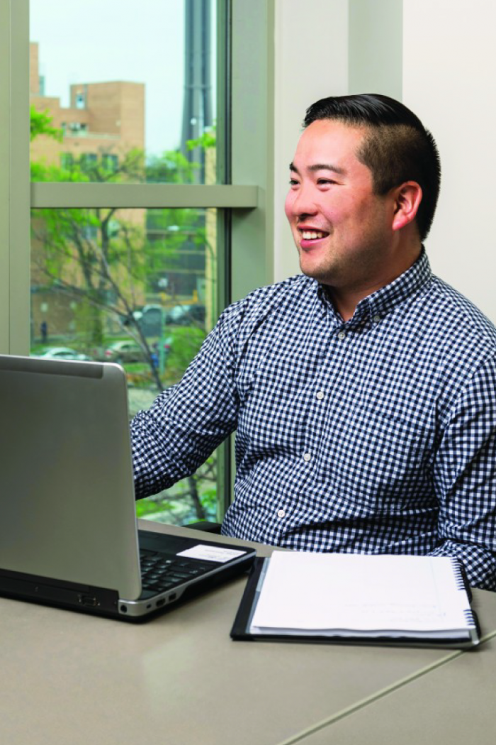 Eliya Ichihashi smiles while working at a laptop.