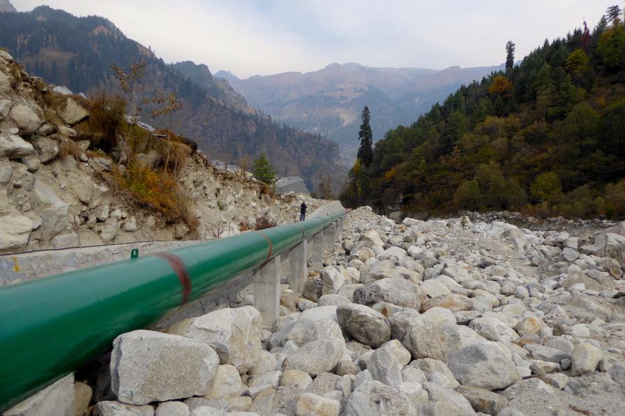 A green pipe running along some rocky terrain.