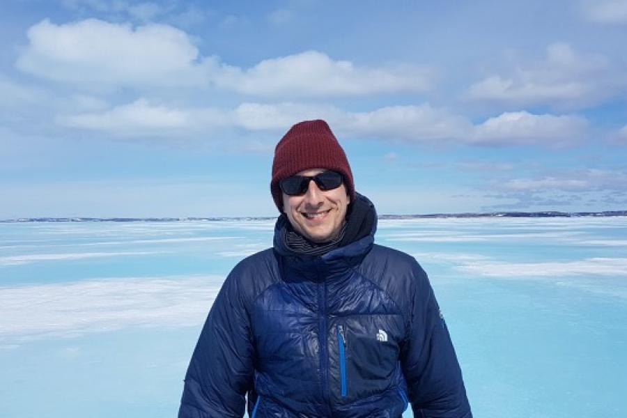 Doctor jens ehn wearing a blue parka and red touque in the arctic.