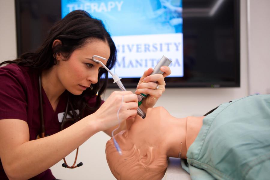 A respiratory therapy student performing an endotracheal intubation on a mannequin. 