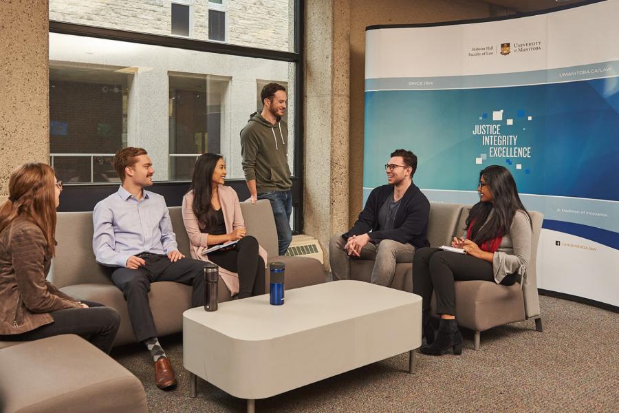 Six students sit together talking in a lounge area.