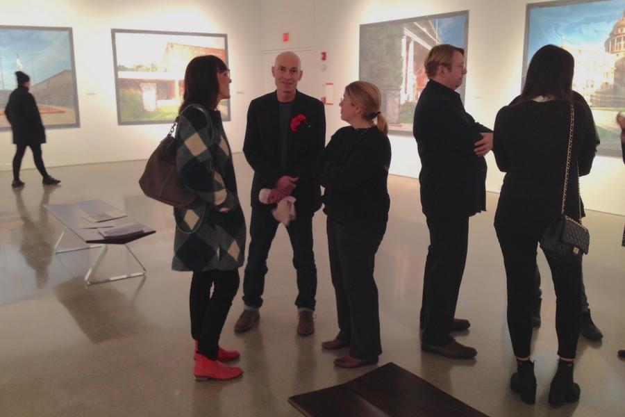 A group of visitors talking at a School of Art exhibition.