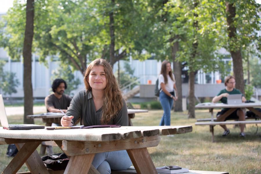 Student sitting at picnic table on UM campus.