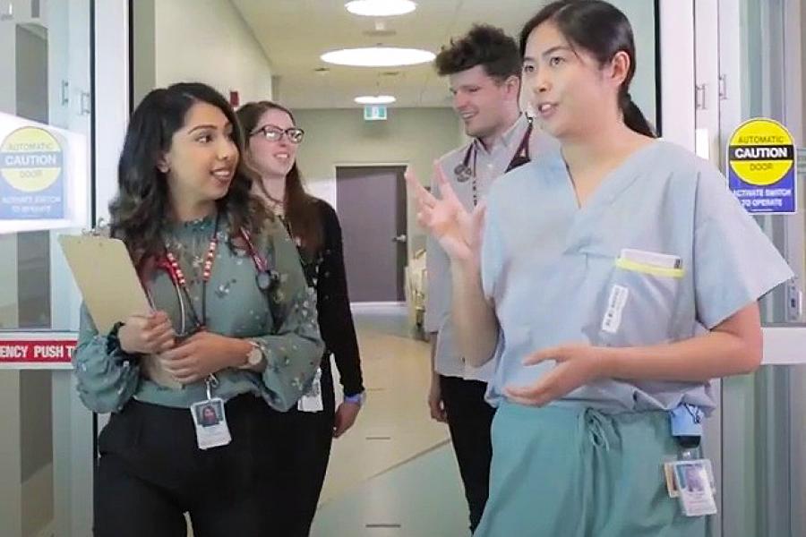 A group of medical residents walking down a hallway, in conversation.