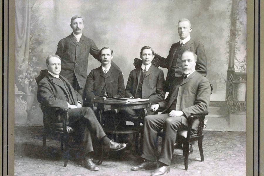 The original six where four men are sitting and the other two men are standing.