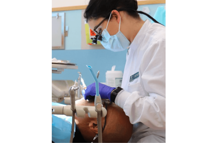 A student practices cleaning a patients teeth. 