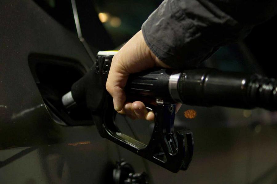 A person is holding a fuel nozzle, refueling their car.