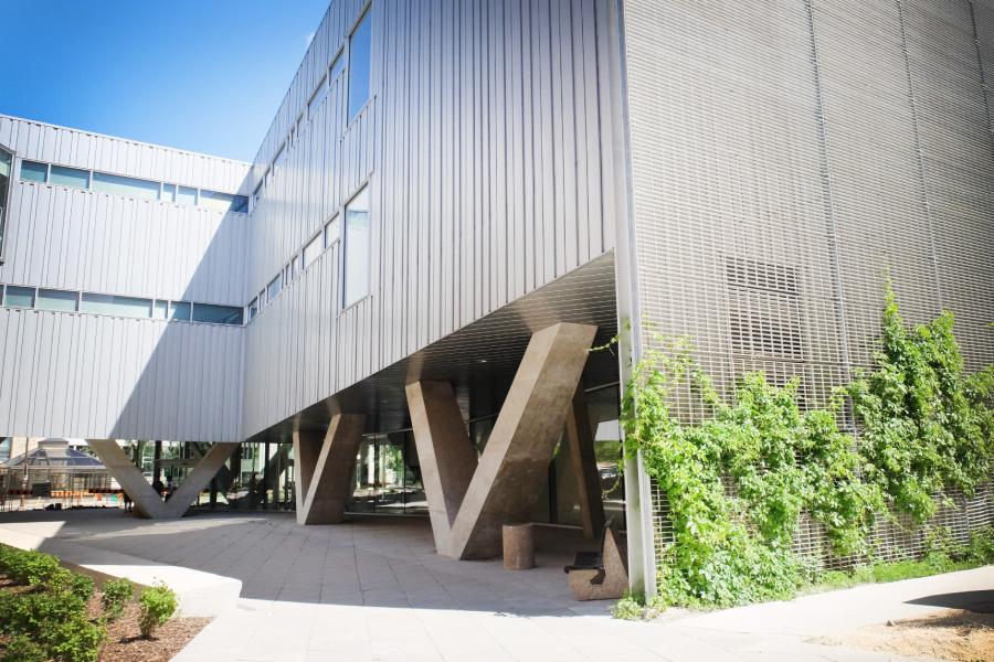 Exterior view of the ArtLab with its unique V shaped cement pillars and vines growing up the aluminum living wall.