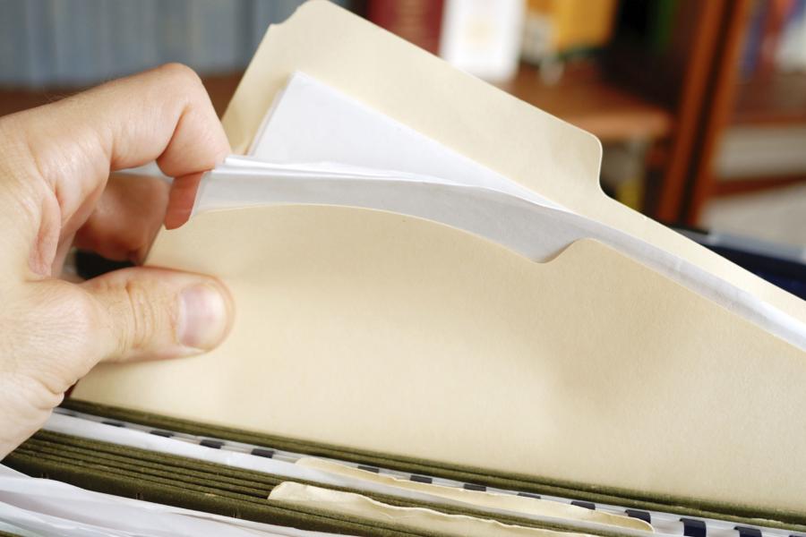 a person pulling a file folder out of a stack.