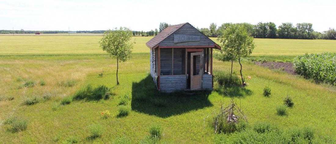 Wood building with trees and grass around it at the Glenlea study.
