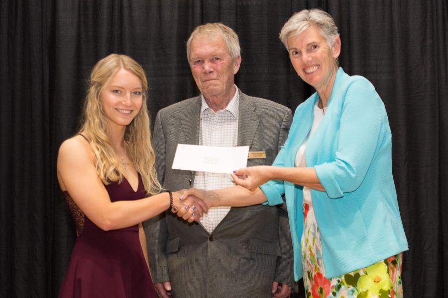 An agriculture student stands on stage to receive an award.