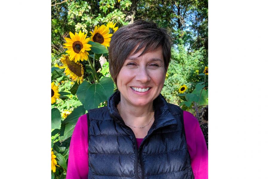 Researcher Joyce Slater standing in front of some sunflowers.