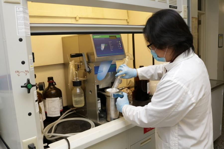 A student pouring from a beaker in the lab.