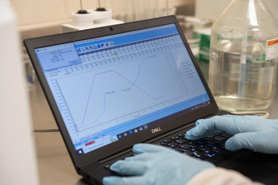 A lab technician works on a laptop