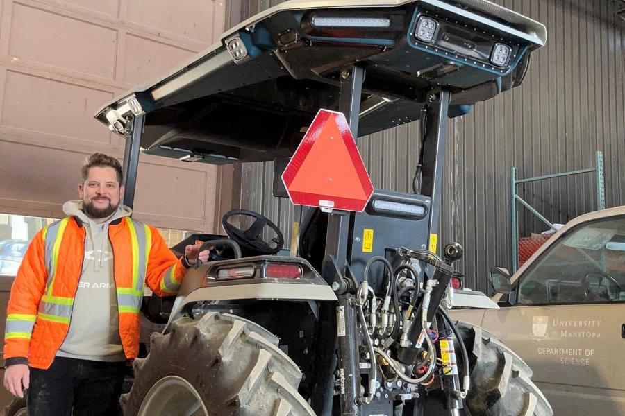 Jason Bourcier stands beside an electric tractor