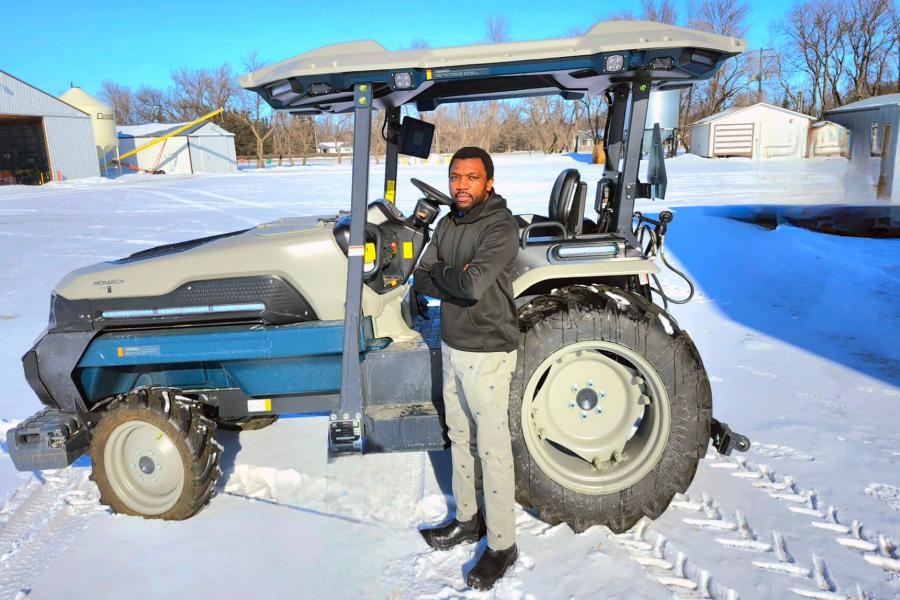 Justice Zhanda stands in front of an electric tractor