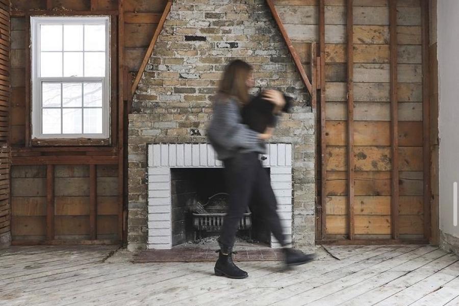 Person carrying baby walking in front of fireplace under construction