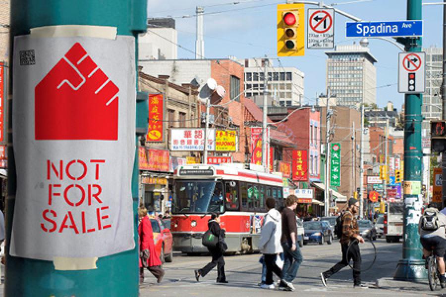 city street with forefront sign that says "not for sale"