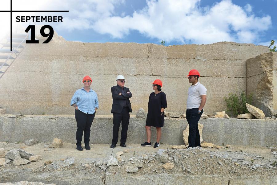 Four individuals wearing construction hats in a quarry.