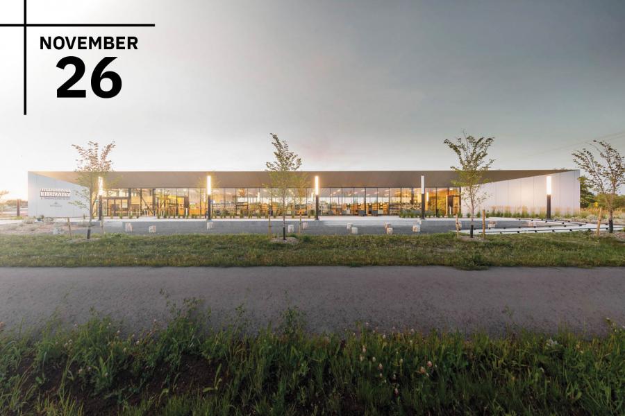 A modern single-story library building with a glass facade and landscaped surroundings.