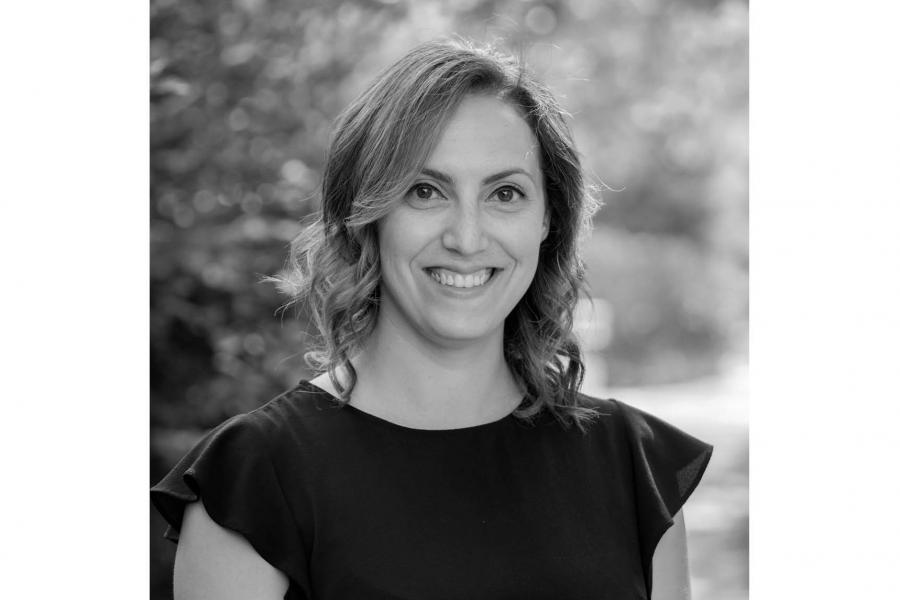 Black and white portrait of a smiling person with wavy hair.