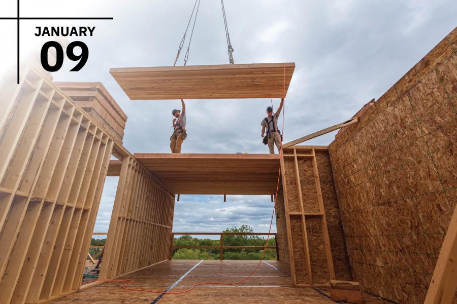 Construction workers aligning a wooden panel on a building site.