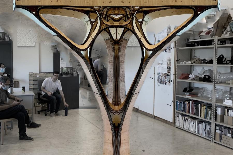 A large, Y-shaped wooden structure displayed in a room with shelves. Several people sit and observe the piece.