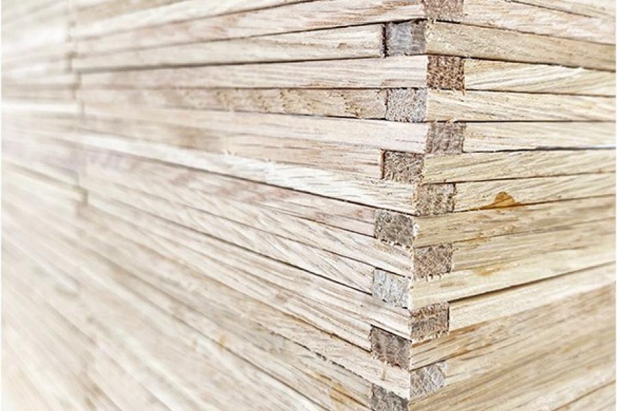 Close-up of neatly stacked thin wooden planks forming a textured wall. The light color and linear pattern create a sense of order and calm.