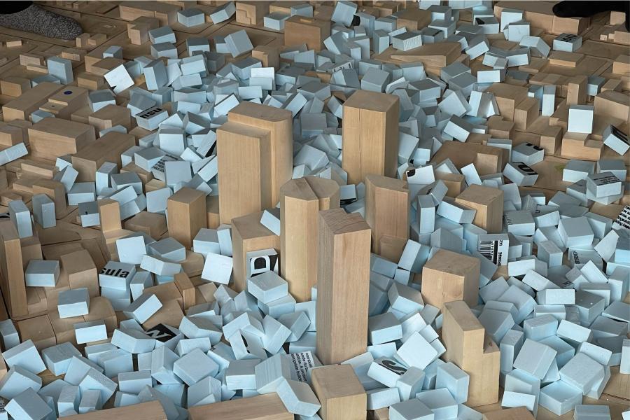 Scattered wooden blocks and small blue pieces form a miniature cityscape on a flat surface, evoking a sense of playfulness and creativity.