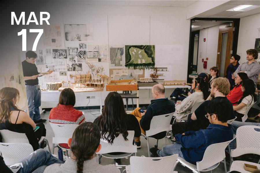 A man presents architectural models to an attentive audience in a classroom. The room is adorned with sketches and diagrams, creating an educational atmosphere.