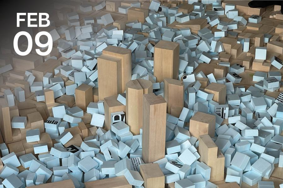 Wooden and foam blocks of various sizes scattered on a surface, resembling a miniature urban landscape.