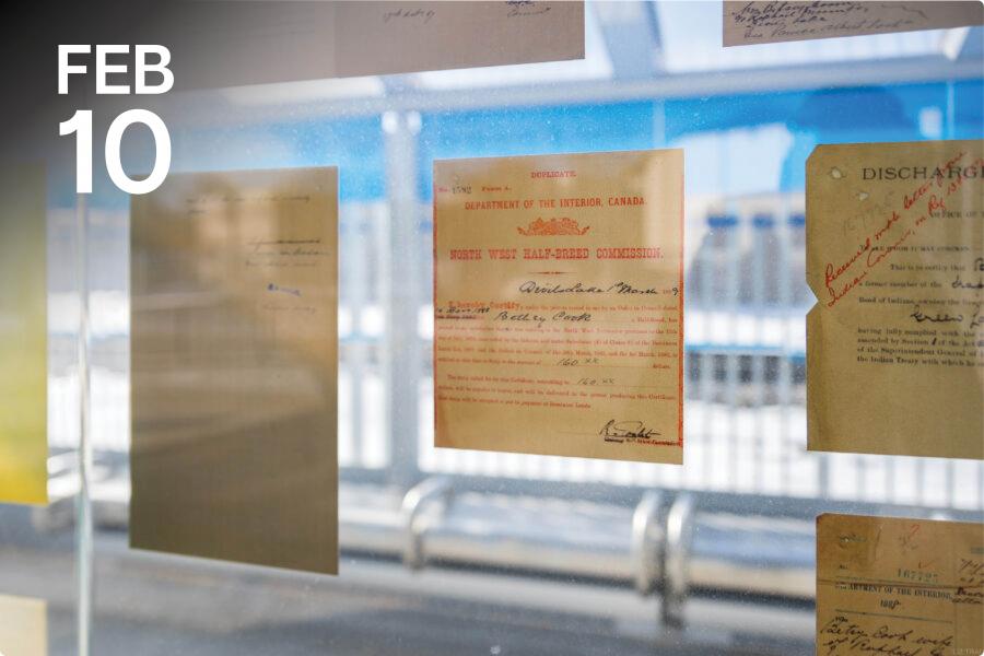 Historical documents, including an official Canadian certificate with red and black text, are displayed on a glass wall.