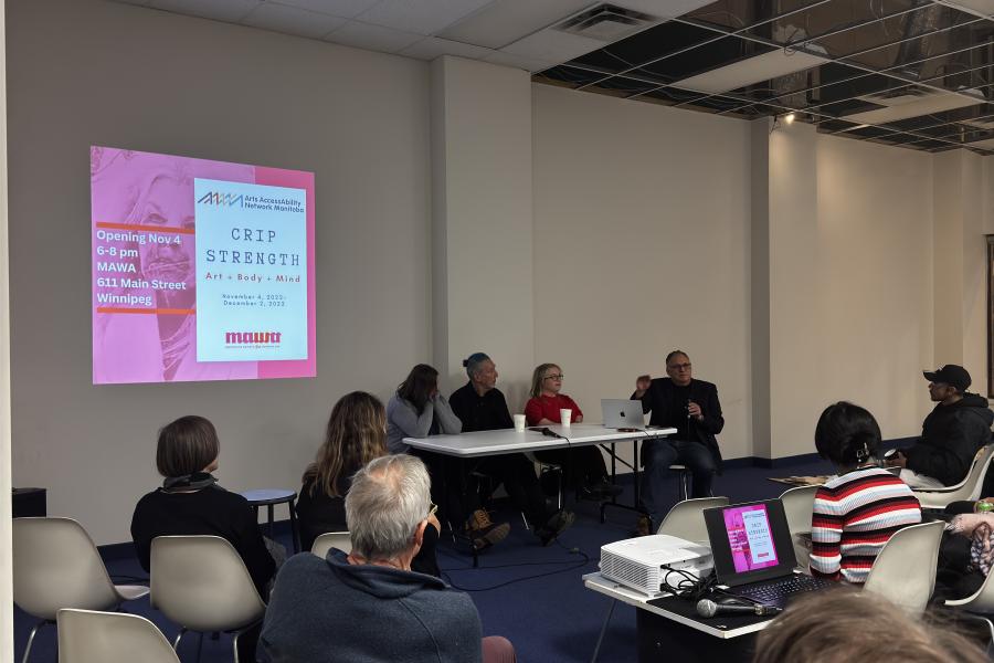 A panel of five speakers sits at a table in a seminar room.
