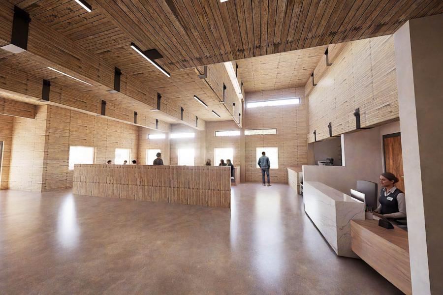 A spacious reception area with wooden interiors, featuring modern desks and soft lighting. People interact at counters, creating a welcoming atmosphere.