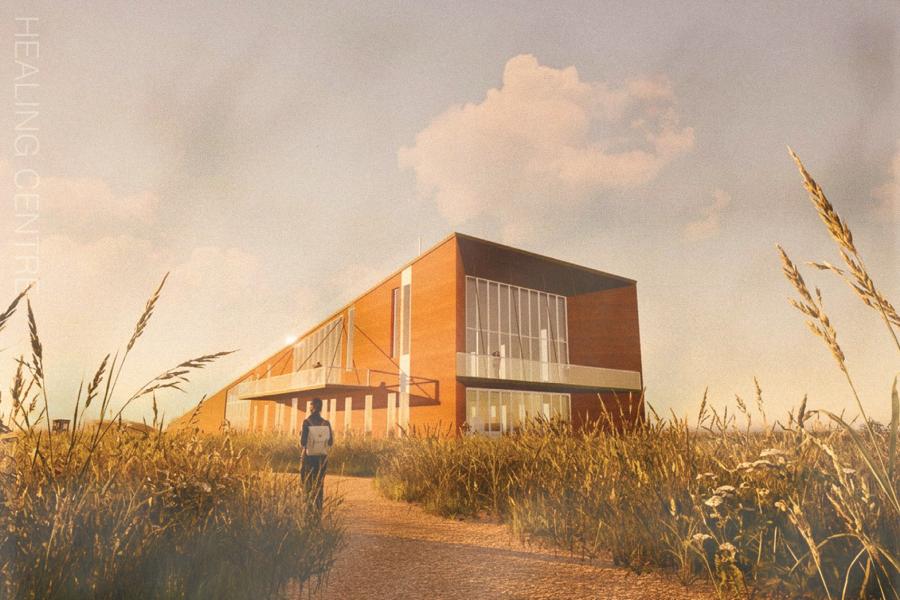 A modern brick building stands amidst tall grasses under a sunny sky. A person walks on a gravel path, conveying tranquility and warmth.