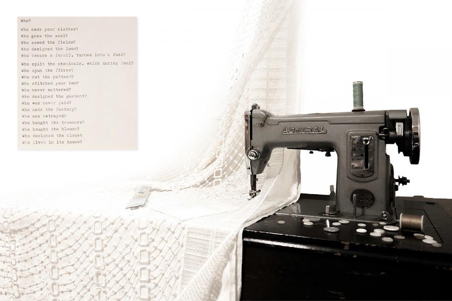 An antique sewing machine on a black table, draped with white lace fabric. 