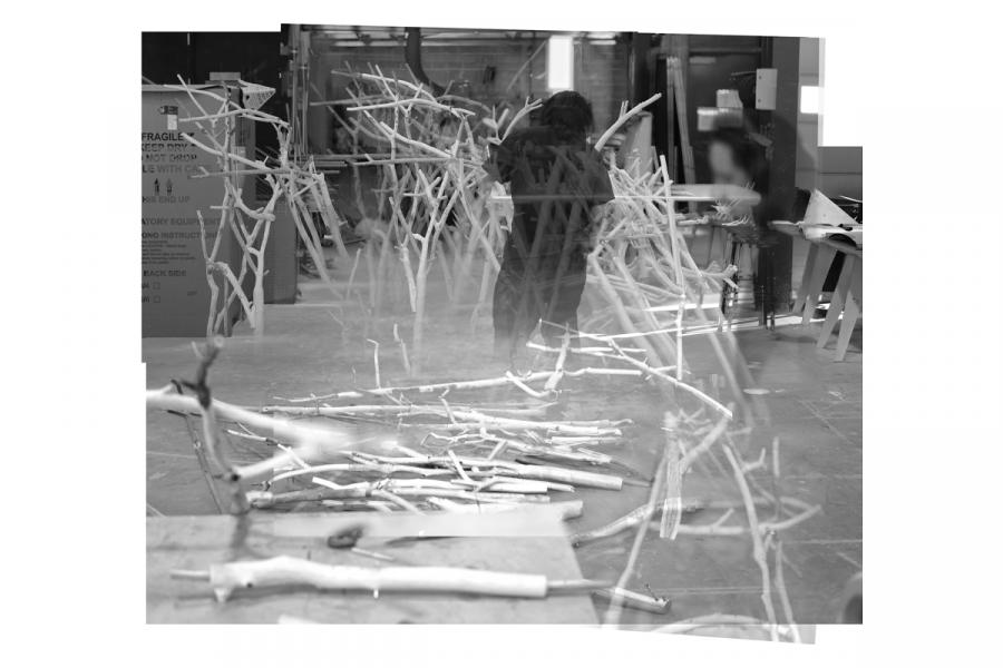Black and white image of a workshop with an artist assembling twig sculptures. 