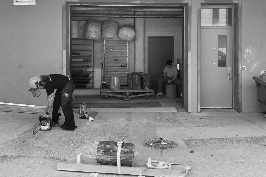 open garage door with person working with chainsaw out front