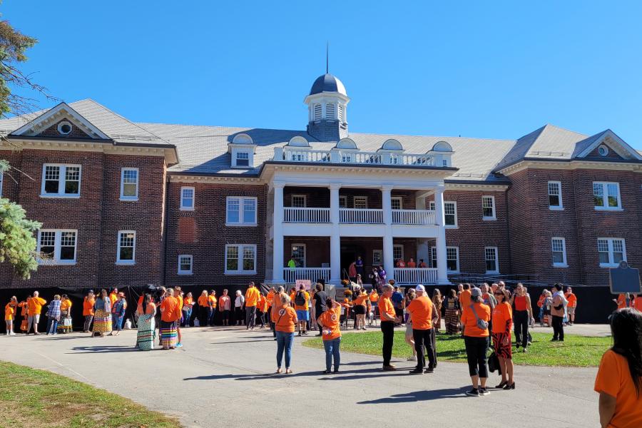 people in orange shirts looking a brick building