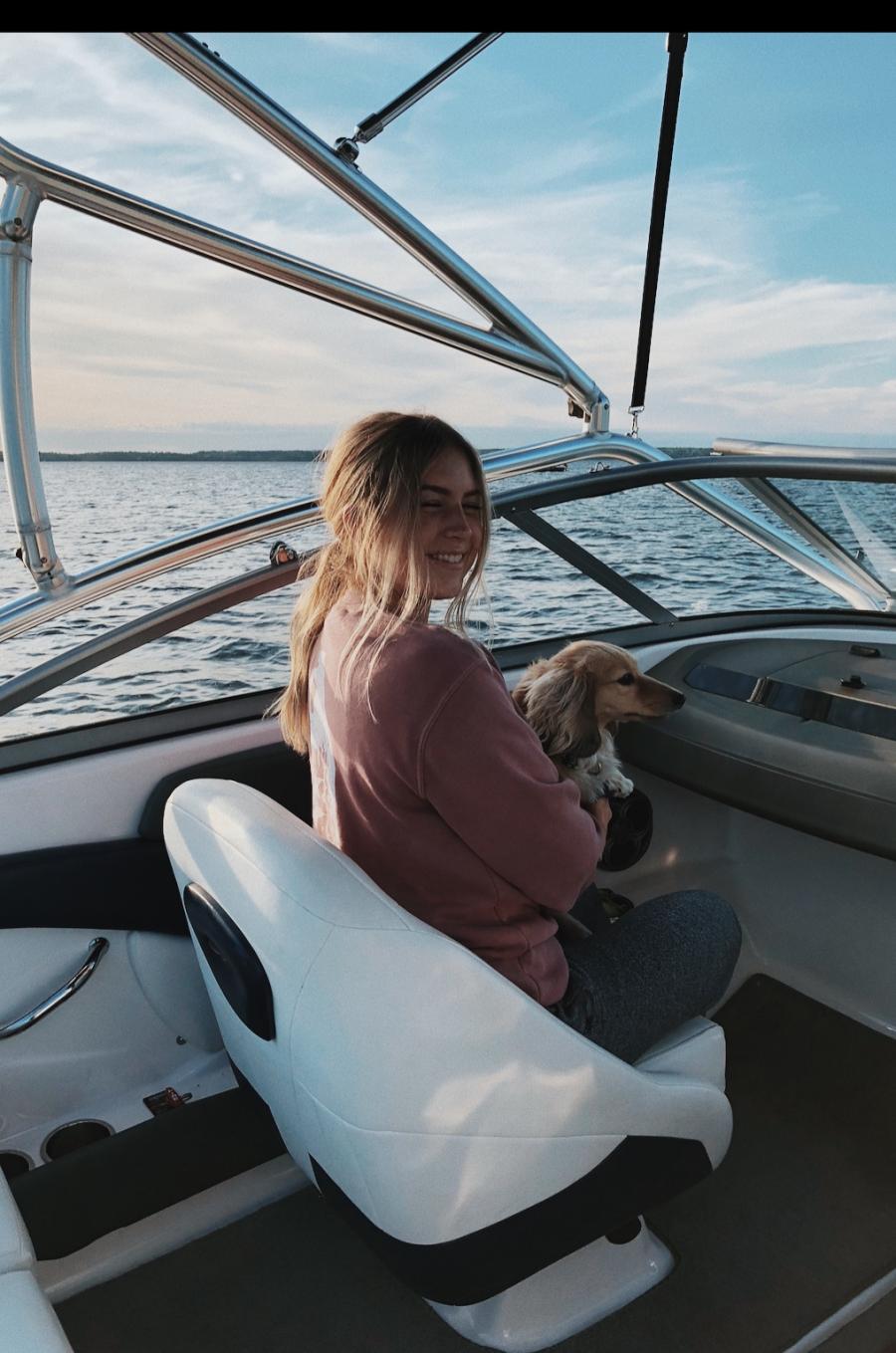 Brooke deRocquigny sitting on a boat holding a dog