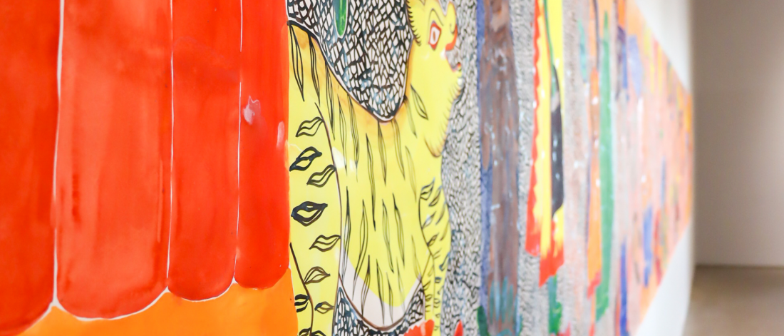 Oblique view along Laila Fazal's mural, highlighting a yellow tiger figure next to red and orange textile-like shapes, emphasizing the mural’s rhythmic composition and hand-painted texture.