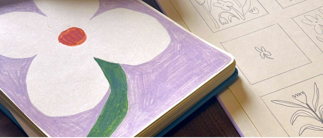 Painted sketchbook page showing a stylized white flower with a purple background and green leaf, beside pencil thumbnail sketches of floral designs.